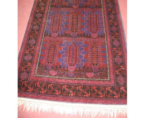 A Persian woollen rust and blue ground carpet , decorated with three rows of stylised medallions within trailing tramline bor