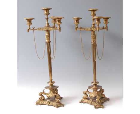 A pair of gilt brass four-light candelabra, the candle-holders each having detachable sconces, on slender reeded column to tr