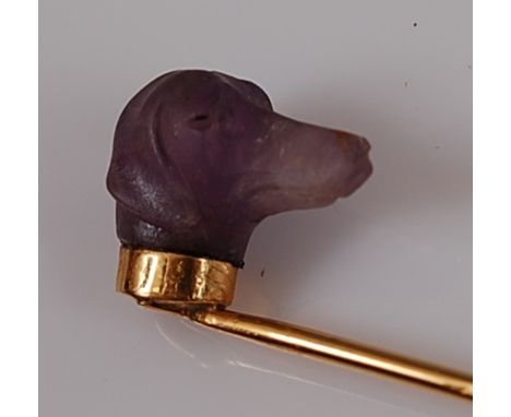 A yellow metal stick pin featuring a carved amethyst dog's head, approx 14.85 x 7mm, gross weight 3.4g, not marked but tested