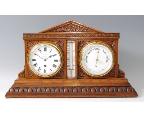 A Victorian carved oak desk weather station, inset with clock and barometer, with central thermometer dial, the clock dial si