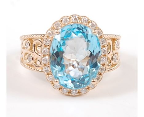 A yellow metal, blue topaz and diamond oval cluster ring, comprising a centre oval faceted blue topaz, claw set within a bord