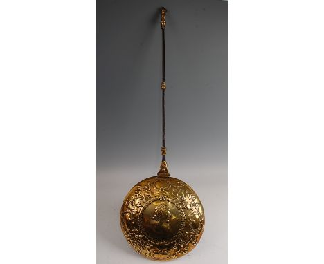 A 17th century Dutch brass warming pan, the circular hinged cover repousee decorated with a profile portrait within a dot-pie