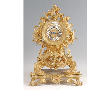 A Rococo Revival gilt brass mantel clock, the balloon shaped swept case having central dial with white enamel raised Roman nu