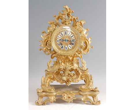 A Rococo Revival gilt brass mantel clock, the balloon shaped swept case having central dial with white enamel raised Roman nu