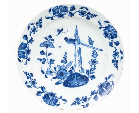 18th century blue and white Delftware dish, decorated in the Chinese style with a bird perched amongst rockery, the border wi