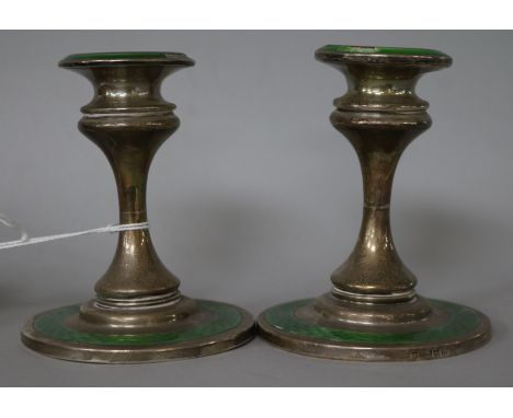 A pair of George V silver and green enamel dwarf candlesticks.