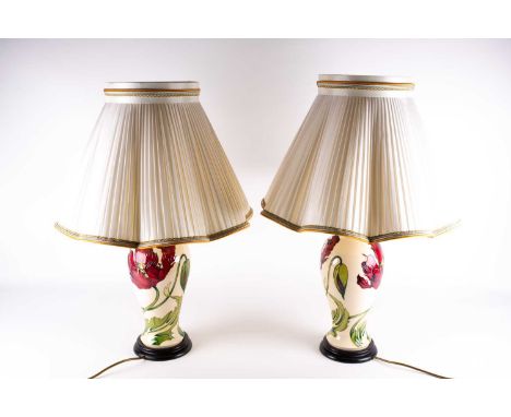 A large pair of Moorcroft 'Poppy' pattern table lamps, the red flowers against a cream ground, each mounted on a wood stand w