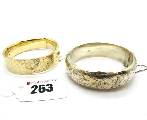 A 9ct Gold Bangle, leaf scroll engraved to the front, hinged to snap clasp (damaged); A Hallmarked Silver Bangle, foliate eng