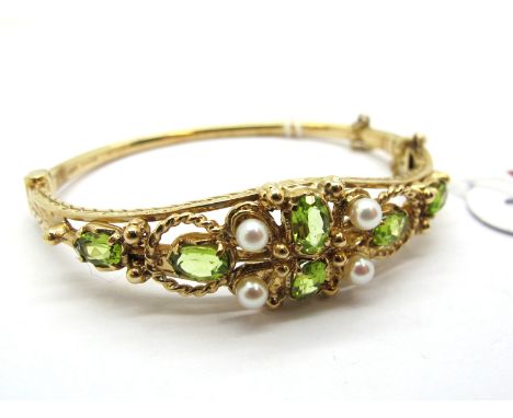 A 9ct Gold Peridot and Pearl Set Bangle, of Edwardian style, claw set, hinged to snap clasp.