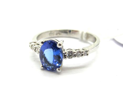 A Modern 18ct White Gold Tanzanite Single Stone Dress Ring, oval four claw set between uniform inset shoulders.