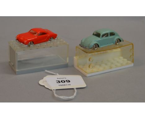 Two Lego System 1:87 scale plastic vehicles: Volkswagen Karmann Ghia in red and Volkswagen Beetle in pale blue/grey. Both wit