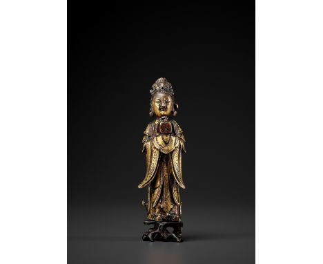 A GILT-BRONZE FIGURE OF A LADY, MING DYNASTYChina, 1368 to 1644. Cast in the form of a standing court lady, holding a gui tab