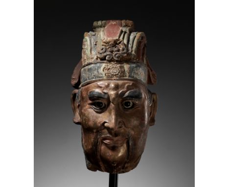 A LARGE PAINTED STUCCO HEAD OF A GUARDIAN KING, SONG TO MING DYNASTYChina, 12th-16th century. Wearing an elaborate headdress,