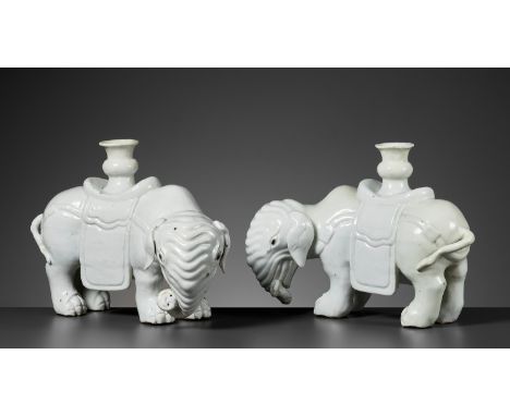 A DEHUA PAIR OF ELEPHANT CANDLE-HOLDERS, EARLY QING DYNASTYChina, 18th century. Massively potted, standing with their heads t