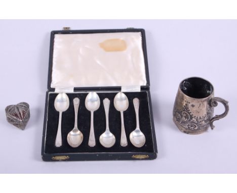 A silver christening mug with inscription, a cased set of six silver teaspoons, a white metal filigree heart-shaped box, 4.7o