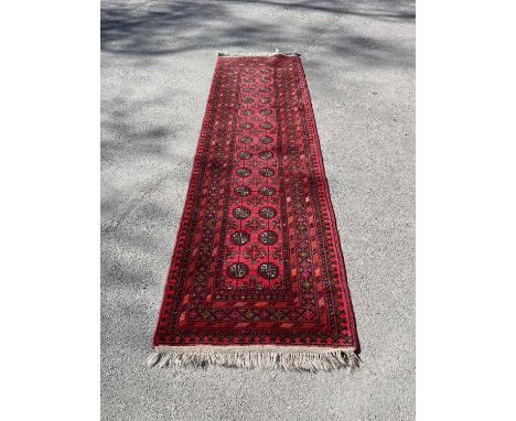 An Eastern red ground runner, with elephant foot type decoration, 285 x 90cm.Condition Report: Lightly worn and a couple of m