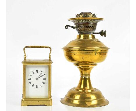 A brass cased carriage clock with white enamel dial set with Roman numerals, height 17cm, together with a brass oil lamp.