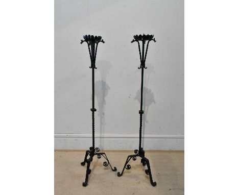 A pair of wrought iron pricket candle stands on tripod supports, height approx 138cm.