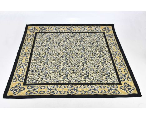 CHRISTIAN DIOR; a black cream and gold 100% silk scarf, with floral design, maker's logo to front right and hand rolled edges