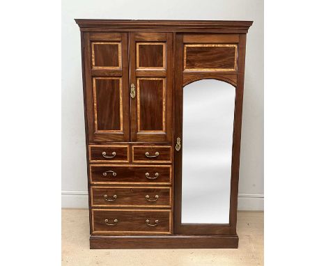An Edwardian mahogany and satinwood crossbanded compactum wardrobe with bevelled mirror door to the right and pair of panelle