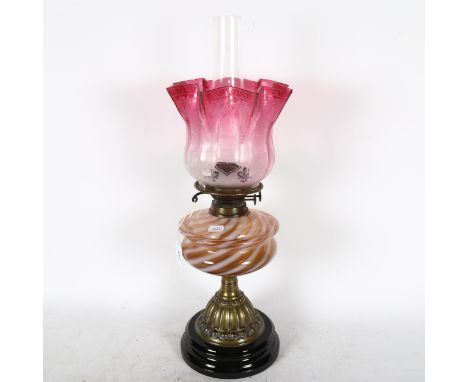 A Victorian embossed brass oil lamp, with coloured glass font, chimney and cranberry glass shade, 54cm 