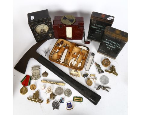 A box containing various military badges and tins, a fireman's axe, a leather multi-tool set etc 