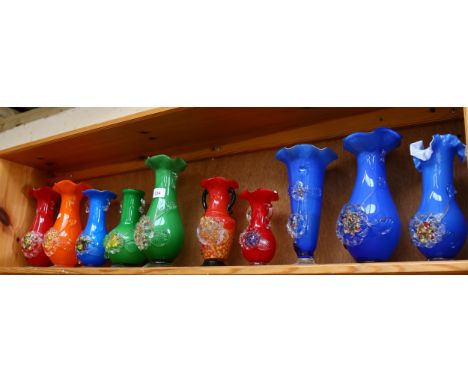 A shelf of colourful 1950s glass vases with applied floral decoration, tallest 25cm 