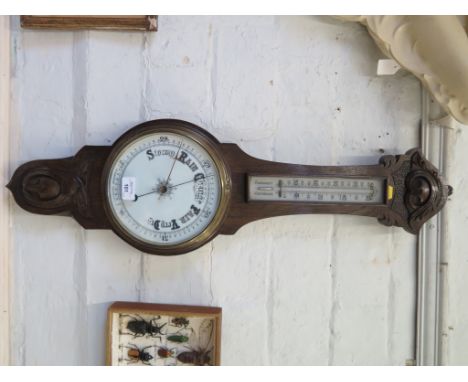 An Edwardian stained oak banjo barometer, with foliate carving, mercury thermometer and aneroid barometer, 83cm high