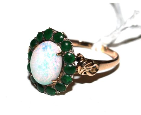 A 14 carat gold ring, set with a central opal with cabochon emeralds around