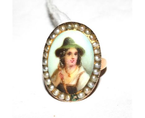 A gold colour metal ring, set with a porcelain plaque of a young man, in a seed pearl frame (one pearl out)