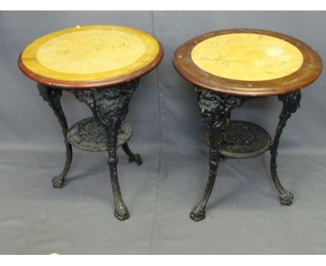 TWO CAST IRON PUB TABLES, reproduction with 59cms diameter mahogany and faux marble effect tops on mask head supports with ci