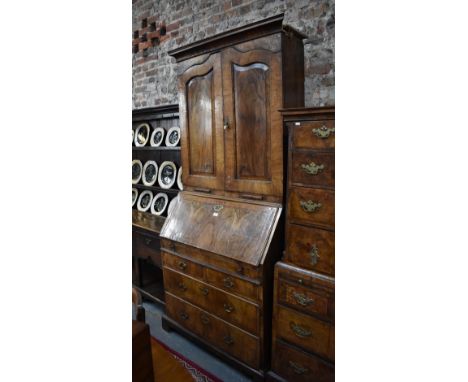 An 18th century feather banded walnut bureau cabinet, the moulded cornice over a pair of fielded panel doors enclosing adjust