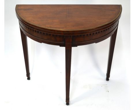 An antique demi-lune tea table, the fold over top with brass inlaid band over a dentil moulded frieze, raised on square taper