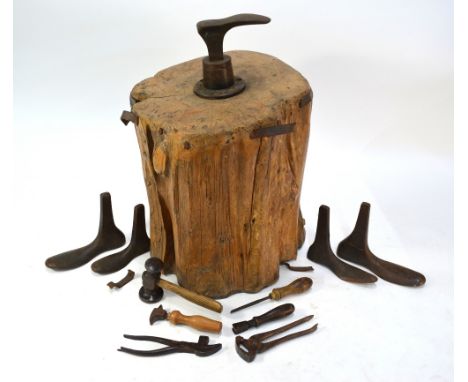 An antique set of cast iron cobbler's lasts, mounted on a heavy tree stump, to/w tools