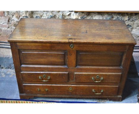 An 18th century oak panelled mule chest, the hinged top over two short and one long drawer on shaped bracket feet, 111 x 50 x