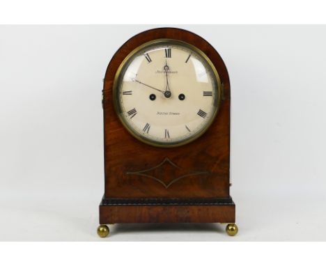 An early 19th century mahogany-cased arch top mantel clock, the white painted 8'' circular convex dial with Roman numerals an