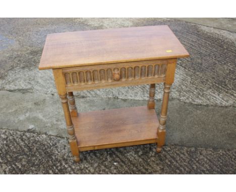 A carved light oak two-tier side table, fitted one drawer, on turned supports, 27" wide x 12" deep x 29 1/2" high 