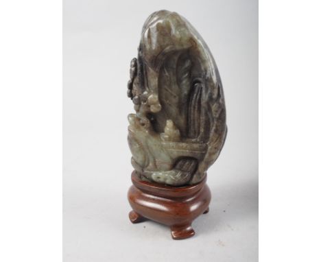 A Chinese carved hardstone boulder, decorated buildings, trees and a figure, on hardwood stand, 4" high overall 