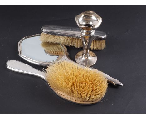 An engine turned silver backed toilet mirror, two silver backed brushes and a silver bud vase, on weighted base 