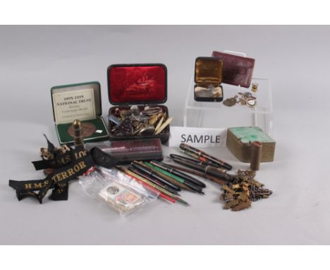 An assortment of fountain pens, badges, pipes, playing cards, cigarette cards and other items 