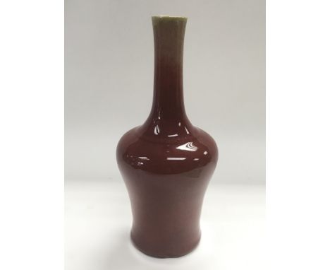 A red glazed ceramic vase with an elongated neck, approx 24.5cm.