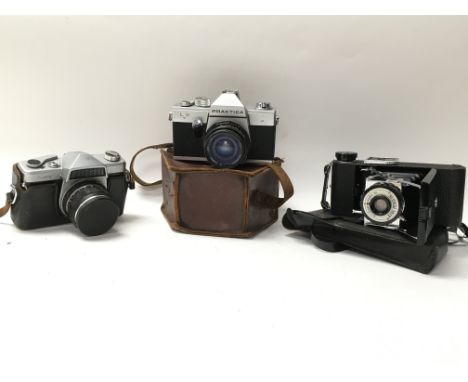 A collection of three vintage cameras. Three brands: Kowa, Praktica, King Penguin. All with original leather cases.