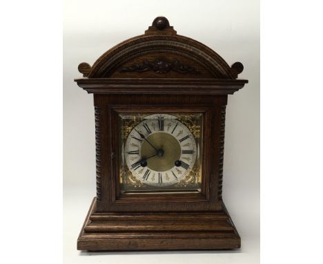 An oak mantle clock, the silver chapter ring with Roman numerals- having key and pendulum