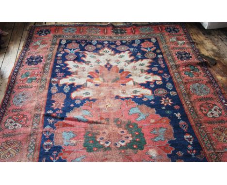 A Caucasian hand woven wool carpet, worked with a central panel of four large flowers against a blue ground with birds and fl