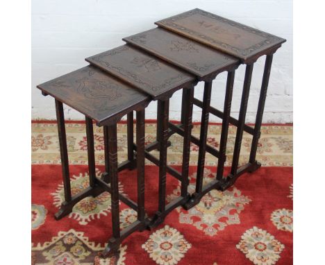 A late Victorian quartetto nest of oak tables of military interest, the largest carved with an armorial and a shield, the thi