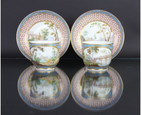 A pair of Sevres porcelain tea cups and saucers circa 1770, each painted with landscape s within two oval panels against a re