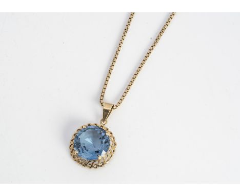 A yellow metal and blue topaz pendant on a 9ct gold box linked chain, the circular cut pendant in claw setting within a pierc