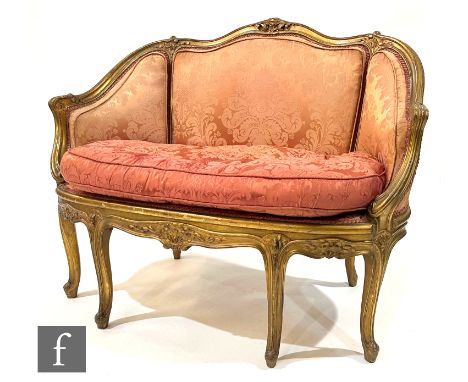 An early 20th Century two seat salon sofa in the Louis XVI style, with foliate detail to the exposed gilt frame, upholstered 