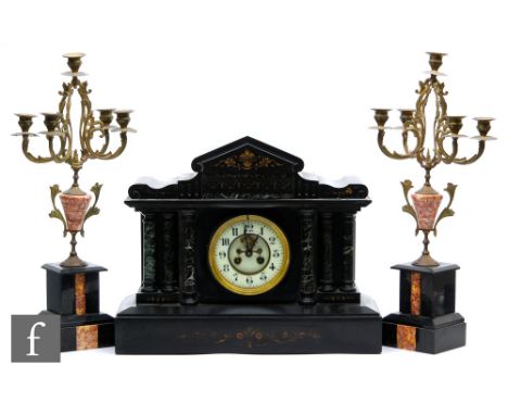 A Victorian slate mantle clock of architectural form and a pair of associated gilt metal four branch candelabrum. (3) 