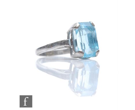 An 18ct white gold single stone aquamarine ring, claw set emerald cut stone to scrolled shoulders, weight 5g, ring size Q. 